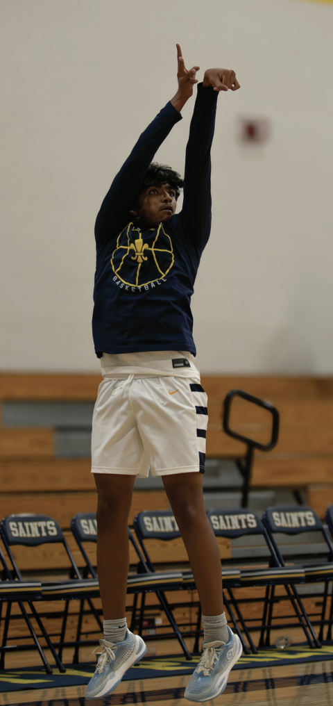 Varsity basketball player Rishi Bokkisam warms up for a game against the Innovation Bulls with a three-point shot.